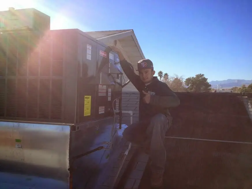 HVAC technician performing Air Duct Cleaning on a rooftop unit in Sparta
